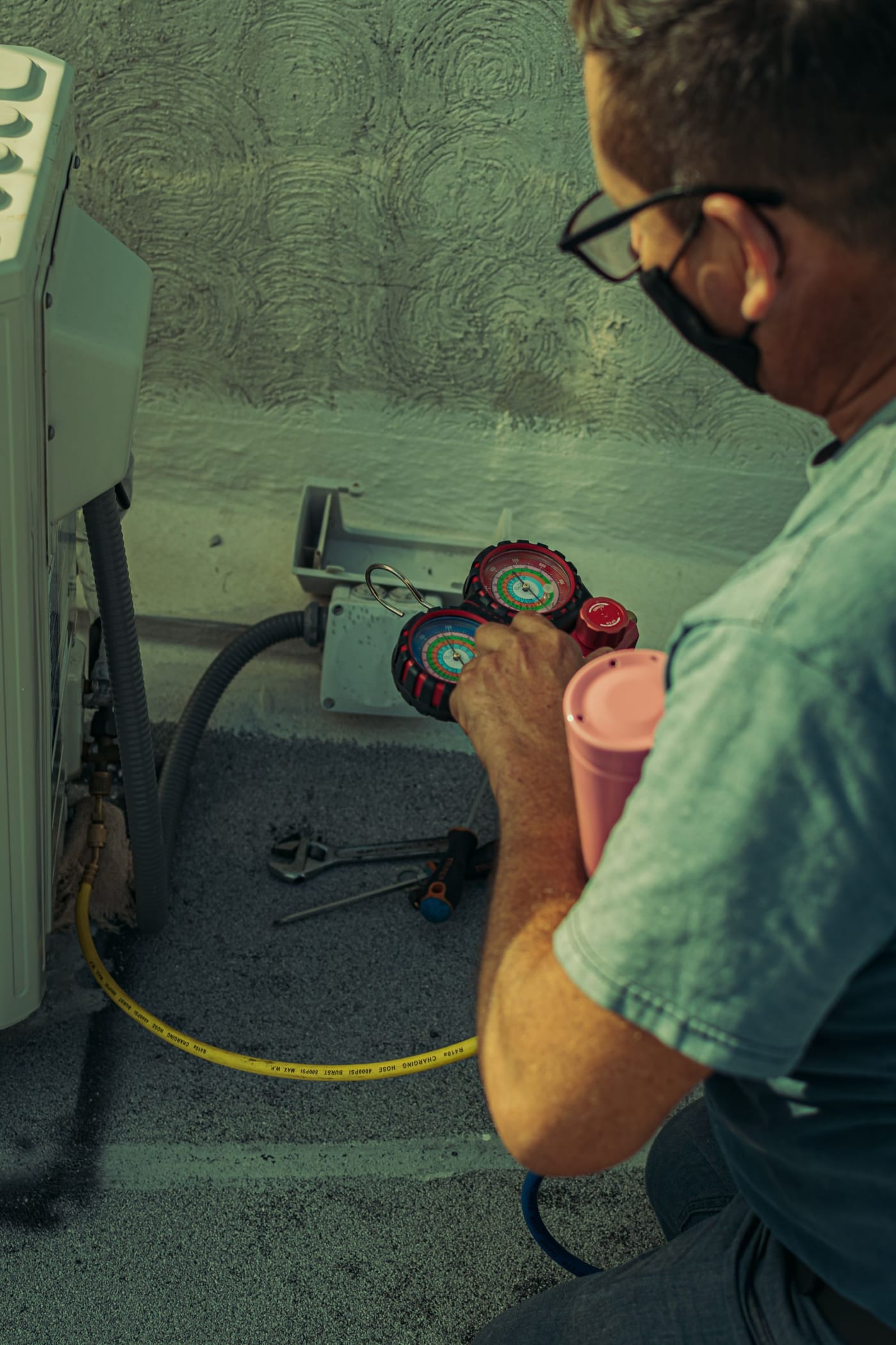 HVAC technician using pressure gauges during an urgent air conditioning repair