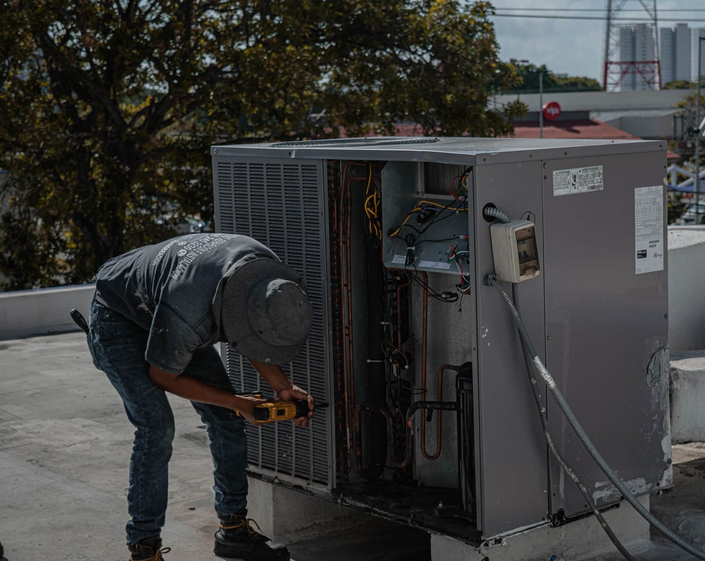 Technician performing hands-on maintenance work on an outdoor air conditioning unit